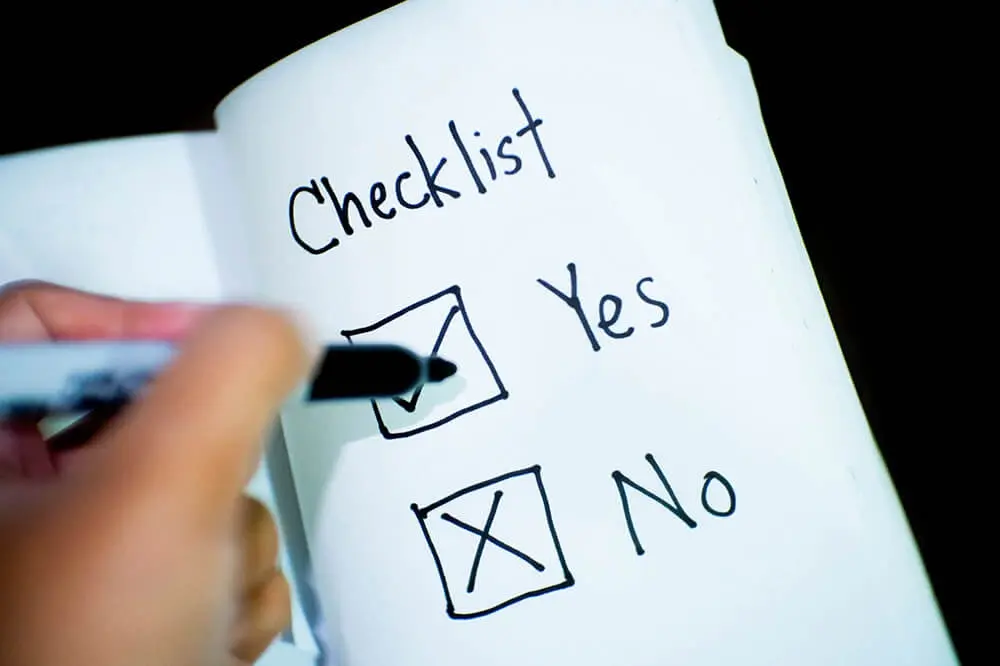 A person checks Yes on a notebook page showing a checklist