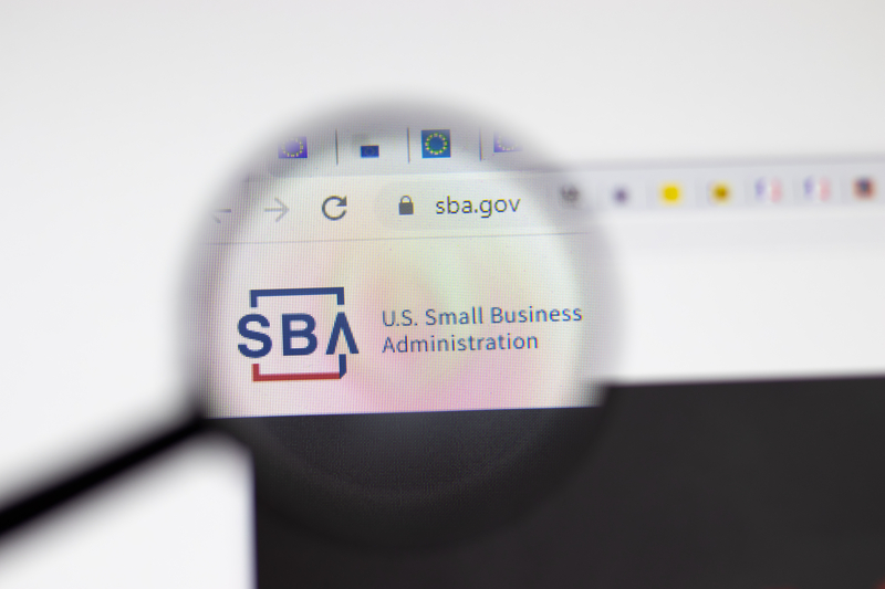 A magnifying glass magnifies the SBA logo on a browser window.
