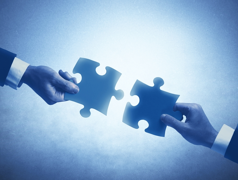 Hands hold out puzzle pieces to fit together