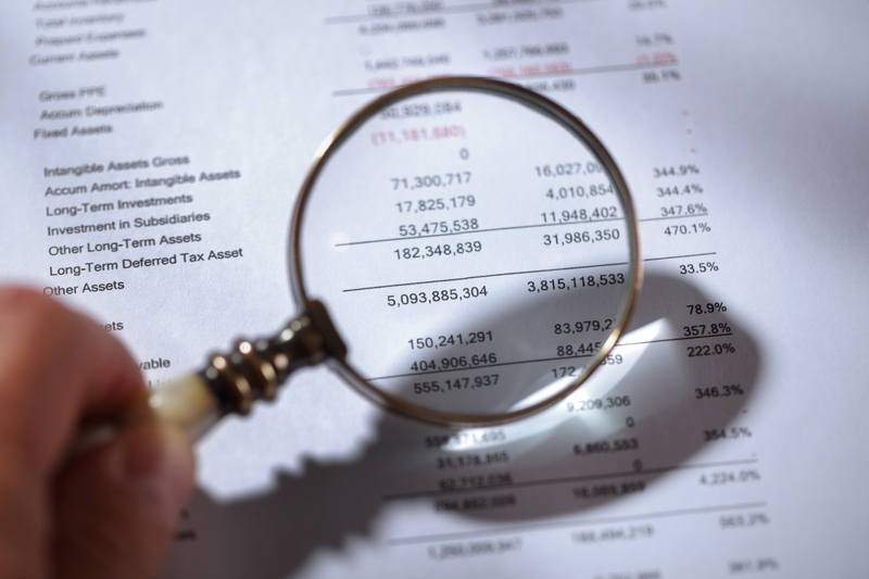 A magnifying glass is held up to a financial statement